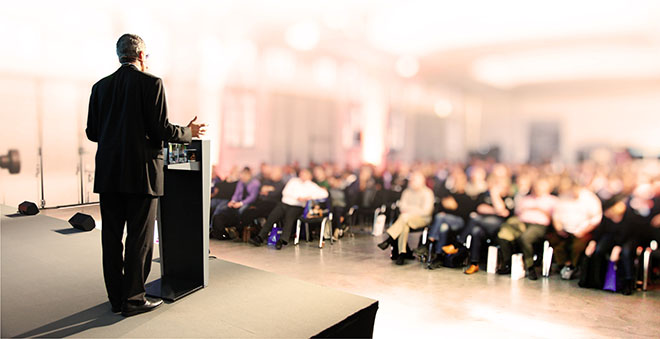 Man giving speech infront of a large audience